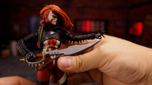 She-Spawn de McFarlane con un arma cruzada delante del torso.