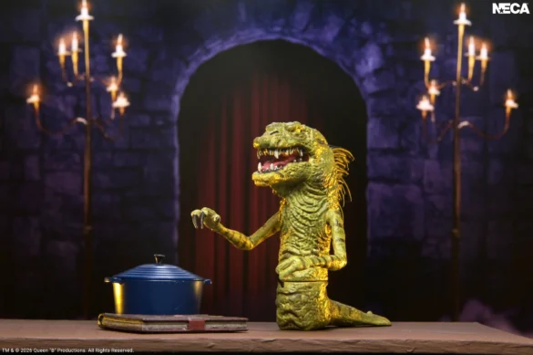 Monstruo verde de Ultimate Elvira de NECA junto a una olla azul sobre una mesa.