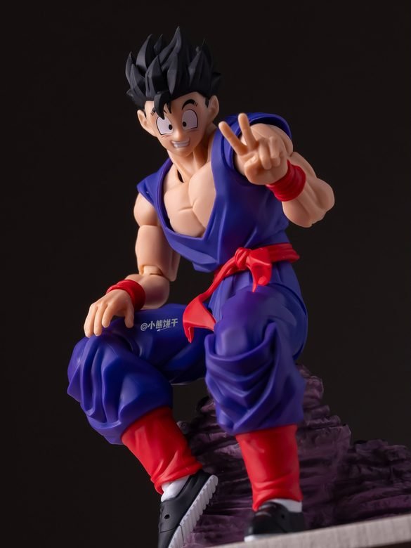 Gohan adulto de HM Studio sentado en una base rocosa con dos dedos levantados.